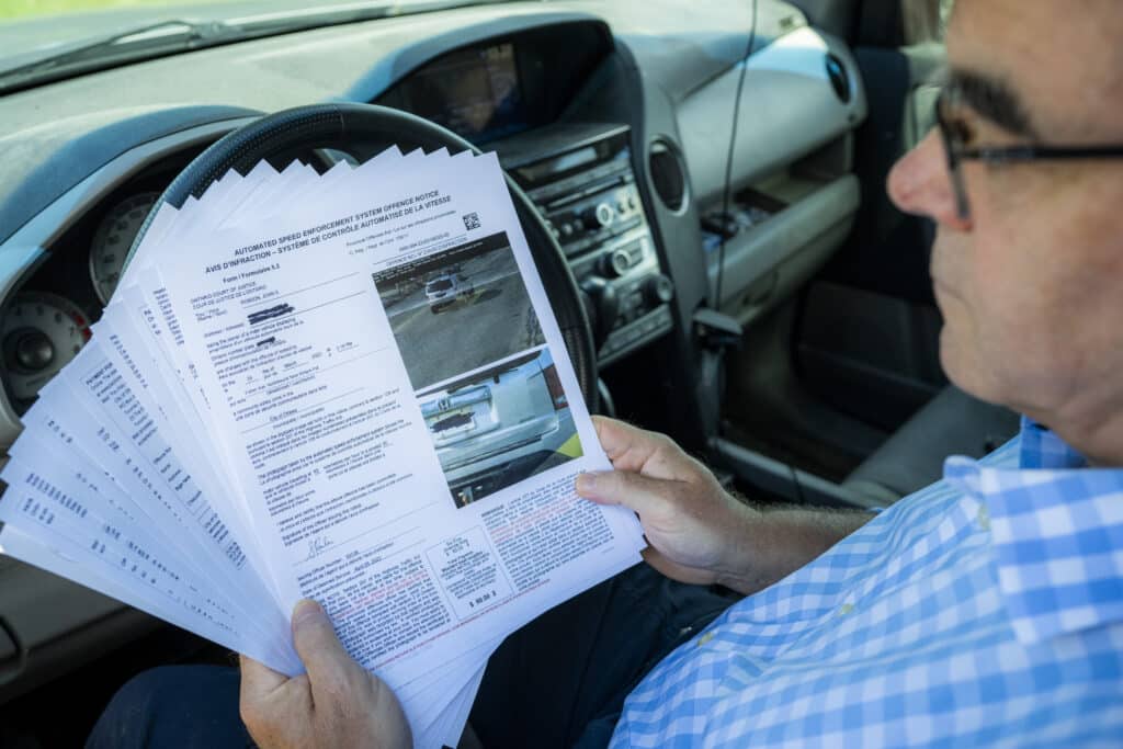Hand over your wallet: Author John Robson with his collection of “automated speed enforcement system offence notices” for going just slightly over the posted speed limit on an Ottawa street designated as a “community safety zone”.