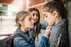 A girl sits alone against a brick wall, bullied – an image of how the HWDSB treated one parent who challenged compelled speech.