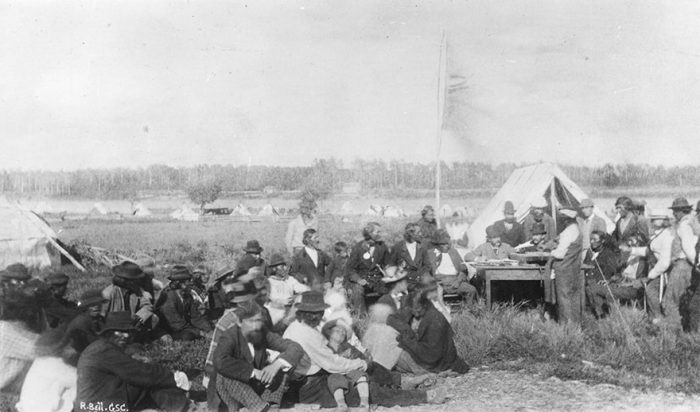 Natives in Manitoba are pictured receiving their treaty money, reflecting Sir John A. Macdonald's commitment to treaty making over conflict.